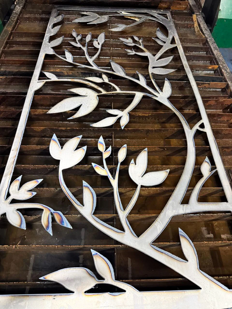 Celosía de acero con diseño de ramas y hojas cortada en plasma
