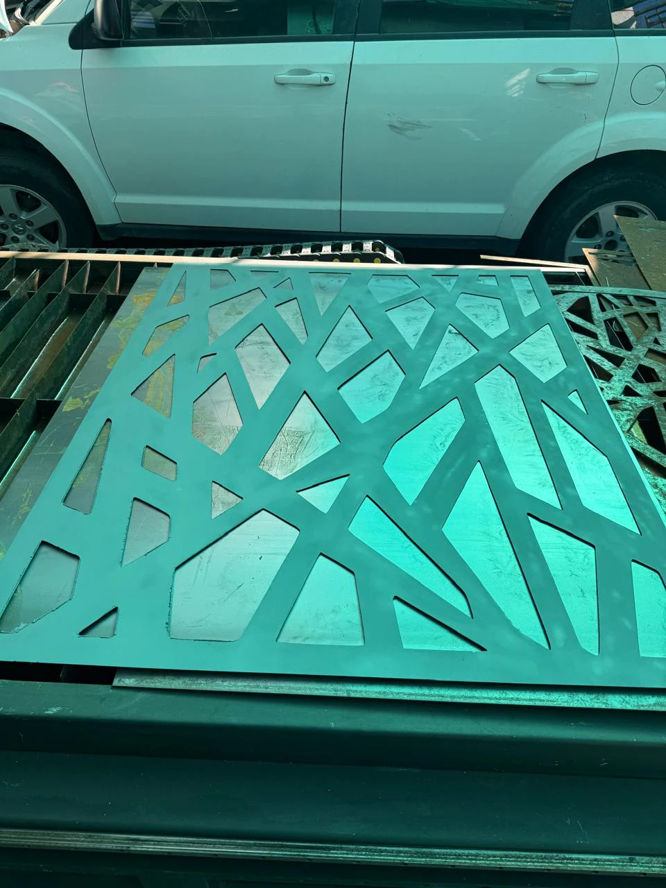 Celosía de patrón geométrico de líneas cortada en plasma y pintada en verde azulado