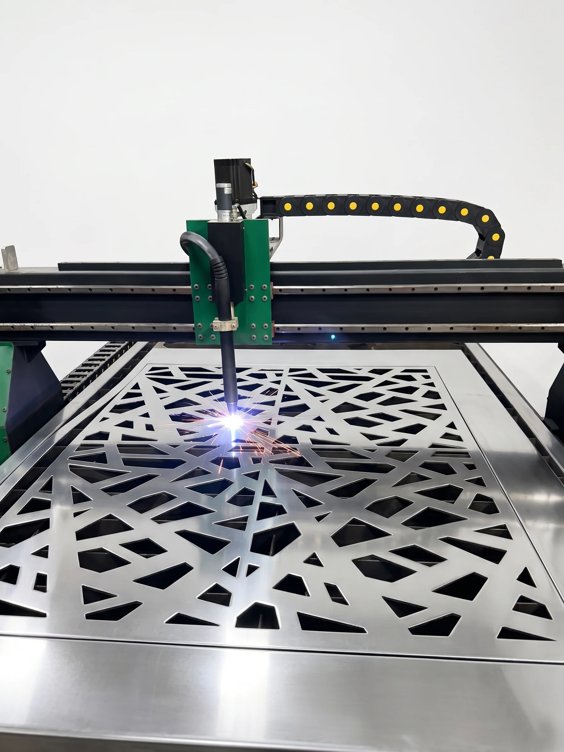 Máquina de plasma CNC cortando una celosía de patrón geométrico sobre una placa de acero